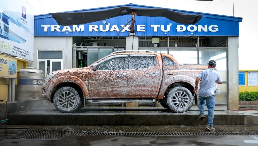 Worker foam-washing a car at Luxury Car Care in Bidar